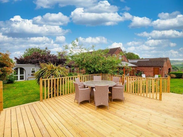 This large decking space in the garden is fit for a party of at least 15 to 20 people. It is raised from ground level, yet still sheltered from neighbouring properties. There is a lawn on each side, with mature bushes and plants.