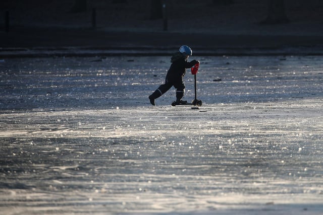A child pushes a scooter on a frozen pond at Victoria Park