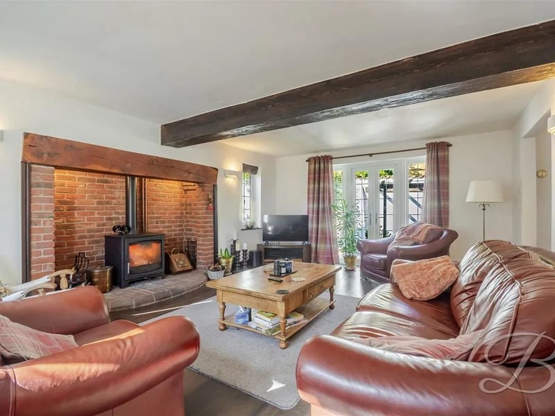 This inviting living space features wooden effect laminate flooring throughout and traditional wooden ceiling beams, creating a warm and characterful atmosphere.