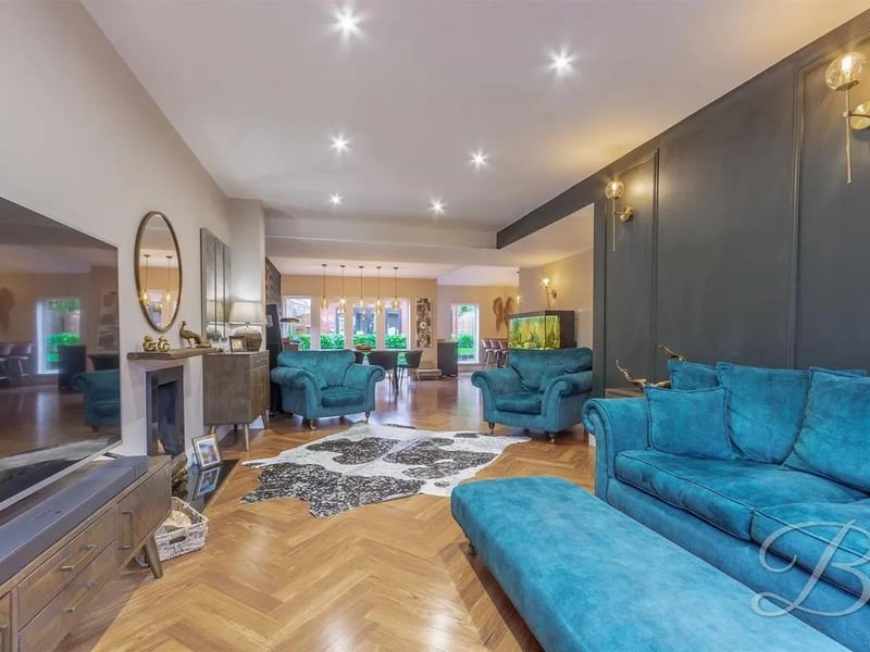 Incredible open-plan space with parquet flooring, open fireplace, panelled feature wall with fitted lighting, underfloor heating, downlights, and window to the front elevation.