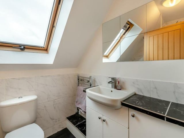 Our tour of the interior of the Clipstone property is completed by the family bathroom on the second floor. A three-piece white suite includes a vanity unit with inset wash hand basin, mixer tap, work surfaces to the side and storage cupboards beneath, a low-flush WC, a chrome, heated towel-rail and a Velux roof window.