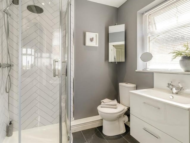 The master bedroom has access to this modern en suite shower room, with chrome fittings. It features a corner shower cubicle with rainfall shower and extra handset, vanity unit with inset wash hand basin and two storage drawers beneath, and low-flush WC. Added bonuses are a fitted storage cupboard, a tiled floor, underfloor heating and three ceiling spotlights.
