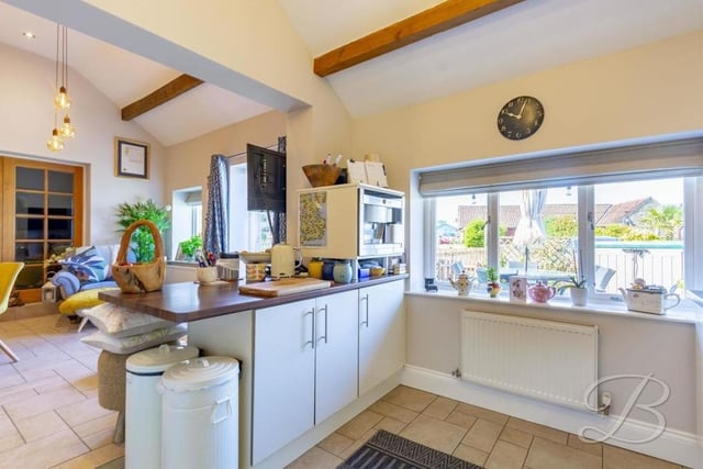 The spacious kitchen also features a gas hob, extractor fan and inset sink and drainer, with a mixer tap above. The floor is tiled.