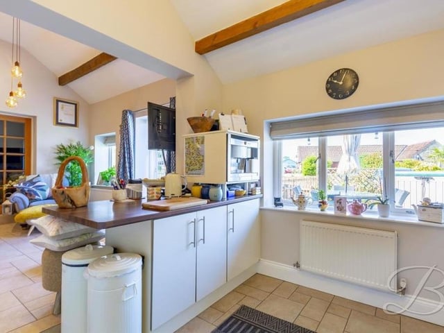 The spacious kitchen also features a gas hob, extractor fan and inset sink and drainer, with a mixer tap above. The floor is tiled.