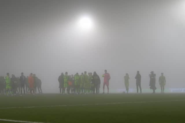 Both sides wait on the pitch while the referee sees what happens with the fog. Photo by Chris Holloway / The Bigger Picture.media