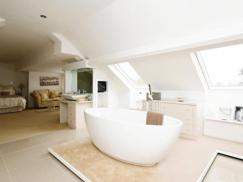 The master bedroom features this sleek en suite bathroom, comprising free-standing bath with central taps and shower attachment, separate shower cubicle, wash hand basin and low-level WC. There is also a heated towel-rail, porcelain tiled floor and two double-glazed Velux windows in the roof.