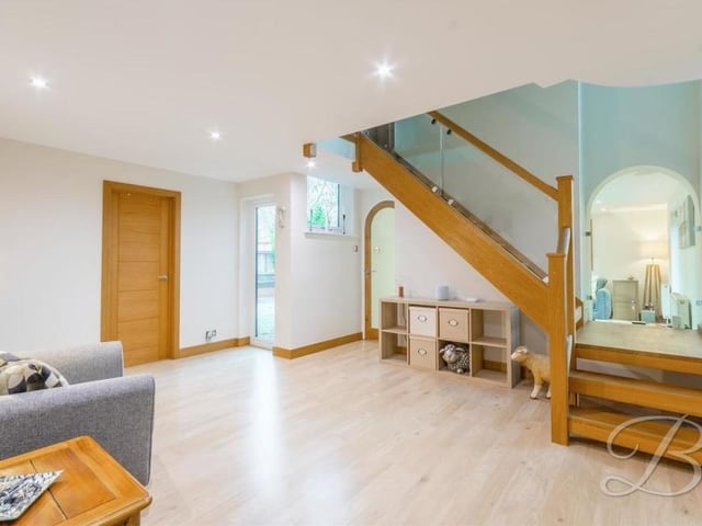 As we prepare to go upstairs at the Harlow Avenue property, let's move through the sparkling hallway. The laminate flooring and downlights guide us to an oak staircase, with a glass balustrade, which rises to the first floor.