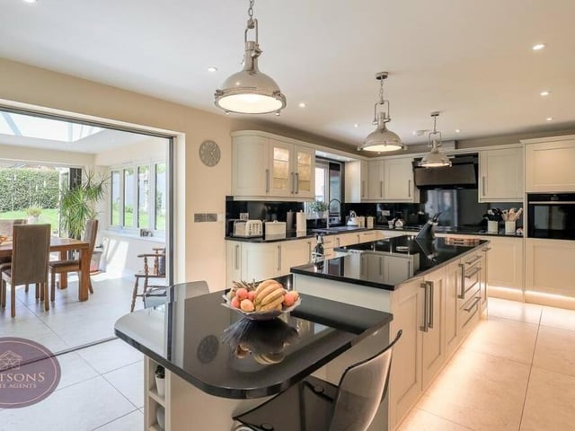 From the orangery, we move seamlessly into the high-spec fitted dining kitchen, with its range of matching wall and base units, granite worktops, inset one-and-a-half-bowl sink and drainer unit, and central island.