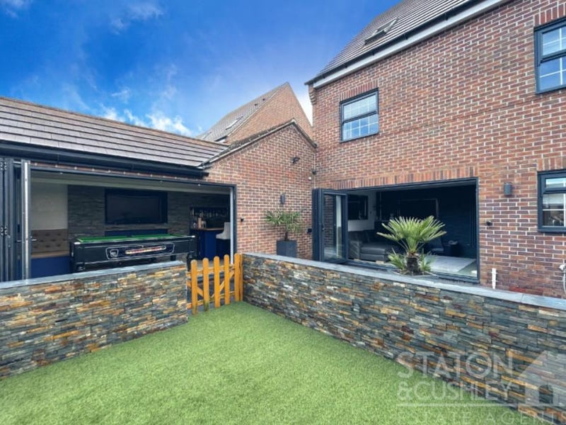 This photo shows how bifolding doors form a gateway to the garden from the games room and bar on the left, and from the kitchen/diner on the right.