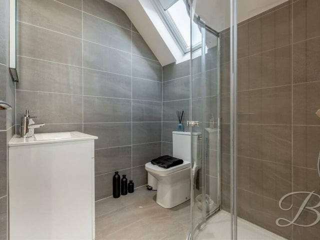 Two of the four bedrooms have their own en suite shower rooms. Here is the first of them, with full-height tiling, a vanity wash hand basin, low-flush WC and enclosed shower.