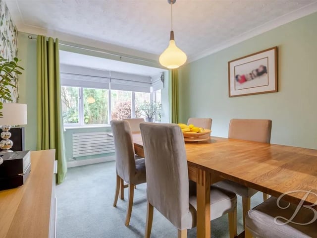 A spacious room with carpeted flooring and a central heating radiator, featuring a large bay window to the rear elevation that fills the space with natural light creating a bright, airy, and versatile space ideal for relaxing or entertaining.