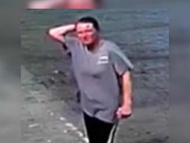 Female with brown hair tied back, grey/blue long t-shirt, black joggers with a stripe down the leg.