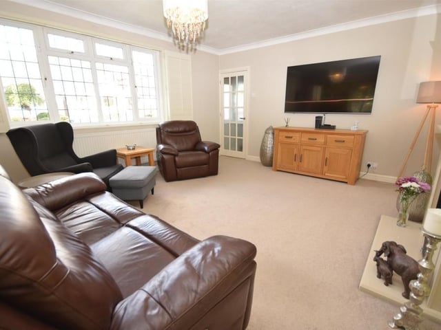 A second image of the open-plan lounge, which opens into the dining room. The large uPVC window, which faces the front of the property, is dressed with elegant, fitted shutters.
