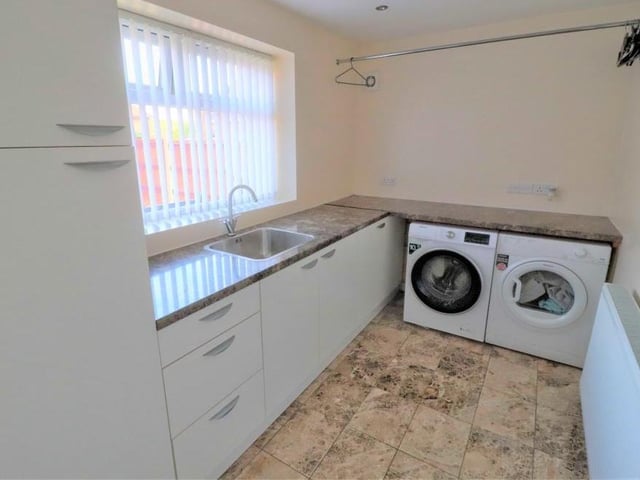 The utility room is large enough for any family. It boasts built-in, modern units, a sink and drainer, plus space and plumbing for a washing machine and tumble dryer. The floor is tiled.
