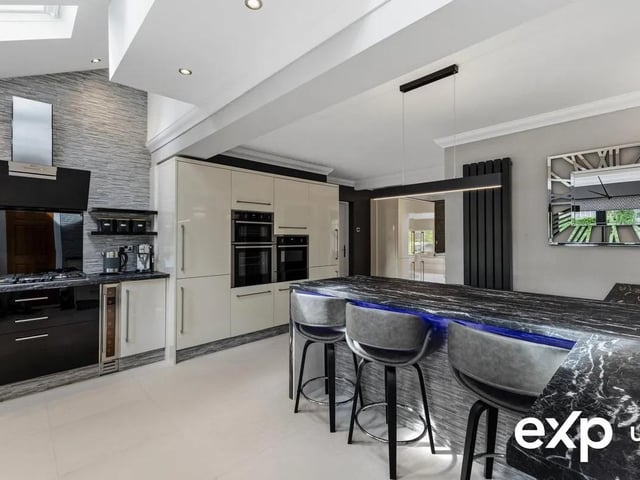 Quality appliances include a five-ring gas hob with extractor above, a double oven, a microwave combination oven, a warming drawer, a dishwasher, a fridge and a freezer.