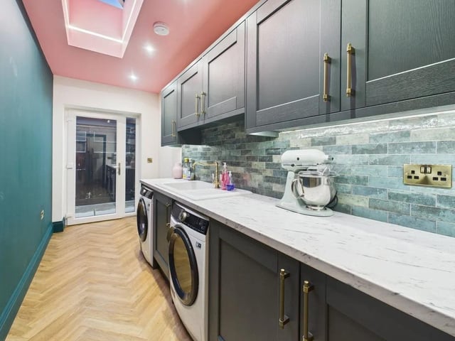 A spacious utility room boasts an integrated fridge and feature ceiling lantern.