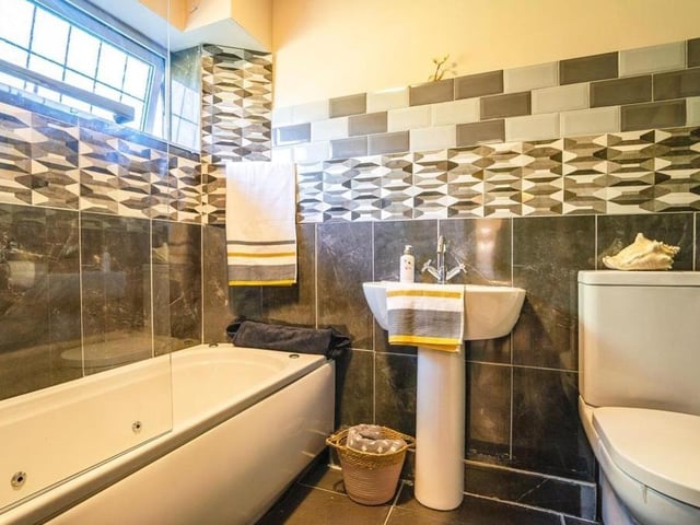 The family bathroom comprises a bath, wash hand basin, WC, tiled splashbacks, tiled flooring and towel radiator.