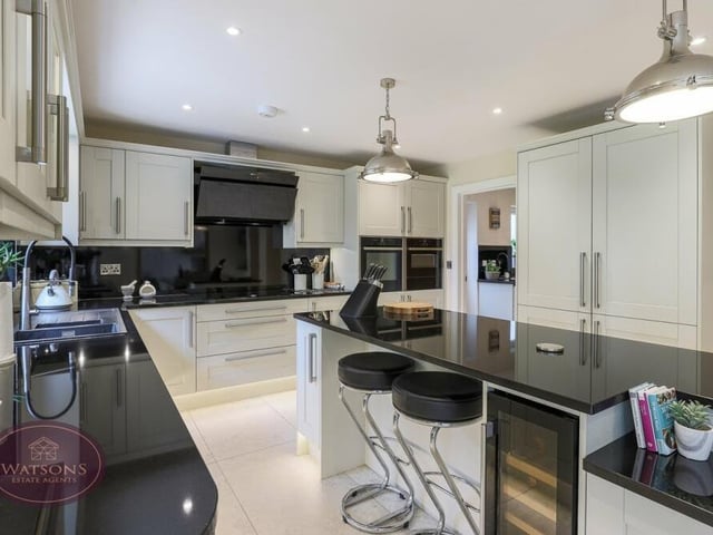 Top-end integrated appliances within the kitchen include a five-ring induction hob with extractor over, a waist-height electric oven, fridge freezer, dishwasher, Neff slide-and-hide microwave and plate warmer.