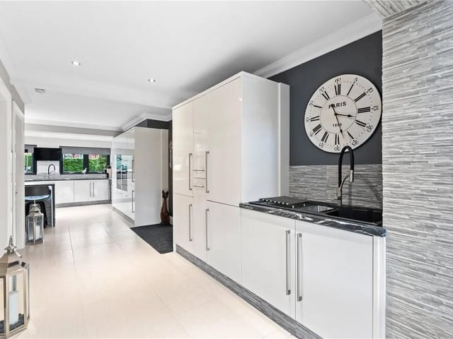 With a range of wall and base units, inset sink and drainer with mixer tap over, tiled splash back, integrated washing machine and tumble dryer, tiled flooring and opening into sunroom with a radiator.