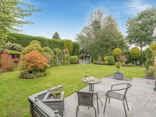 This photo captures the patio seating area against the backdrop of a beautifully presented rear garden, surrounded by a superb display of mature trees and shrubs.
