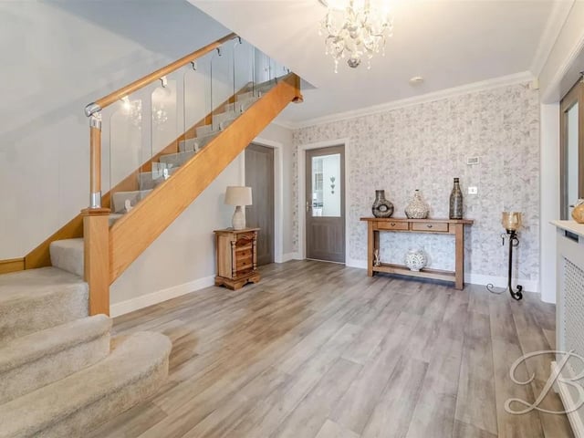 The spacious entrance hallway features laminate flooring, stairs to the first floor, and doors leading to the main living areas.