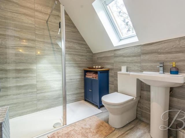 The en suite to the second bedroom, with its walk-in shower, low-flush WC and wash hand basin.