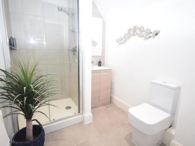 The principal bedroom flows through to this en suite, which is designed with contemporary fittings that comprise a shower cubicle, wash basin in vanity unit and low-flush WC.