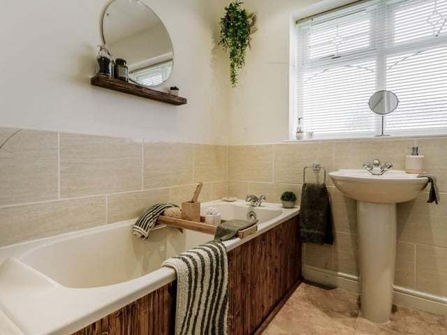 Next to the office sits this family bathroom. A panelled bath with mixer tap and tiled surround is complemented by a pedestal wash hand basin with mixer tap, and low-flush WC. With a tiled floor, part-tiled walls an four ceiling spotlights, the room also contains an airing cupboard housing a pressurised hot-water cylinder.