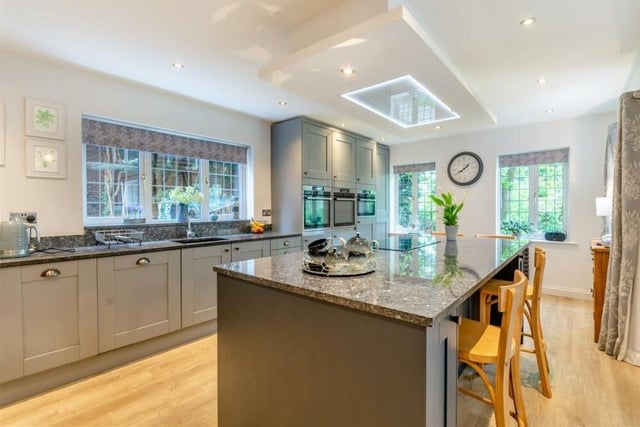 The kitchen has a comprehensive range of contrasting dark blue and grey cabinets, comprising wall cupboards, base units and drawers. An inset Franke sink, with mixer tap and drainer, is built into a worktop, while there are also pull-out larder units providing extensive storage space.