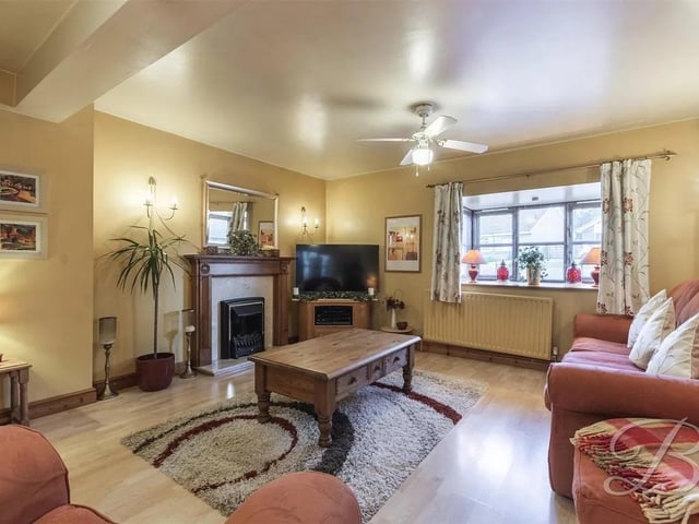 The cosy living room has laminate flooring, feature fireplace, access into the store room and a window to the front elevation.