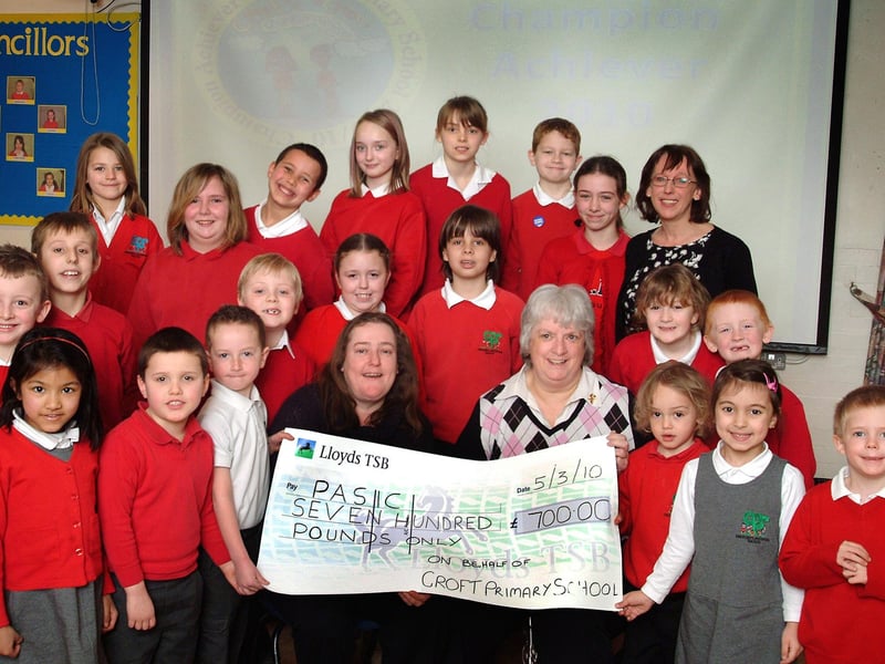 Pupils from Croft Primary School in Sutton are pictured with their head teacher, Lizzie Blount, alongside representatives from PASIC, Maria Tucker (seated left) and Bea Brunton (seated right). They are holding a cheque for £700, which was raised in just one week through a pyjama disco, cake sale, and non-uniform day in 2010.