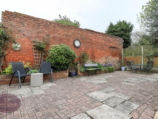 This paved patio area at the back of the Bagthorpe house is full of character, with quirky brick wall and multiple seating areas.