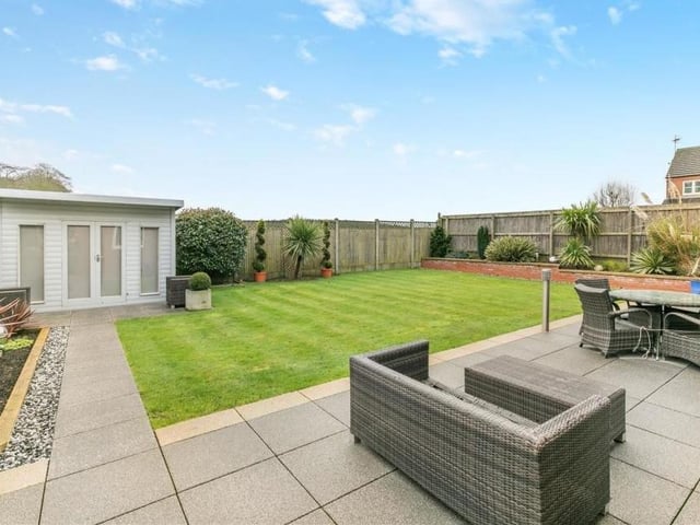 Time to step outside now, and into the back garden, complete with a paved patio that extends the width of the property, offering ample seating space. To one side of a central, manicured lawn is an outside office, equipped with power and light. Ideal if you work from home.
