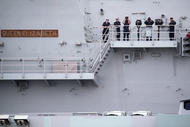 Crew members stand outside one of the two islands on the flight deck as HMS Queen Elizabeth leaves Portsmouth. Picture: Andrew Matthews/PA Wire