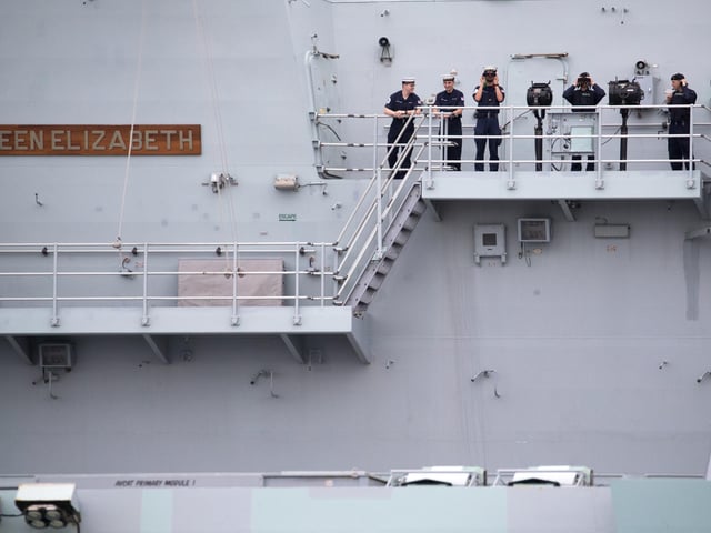 Crew members stand outside one of the two islands on the flight deck as HMS Queen Elizabeth leaves Portsmouth. Picture: Andrew Matthews/PA Wire