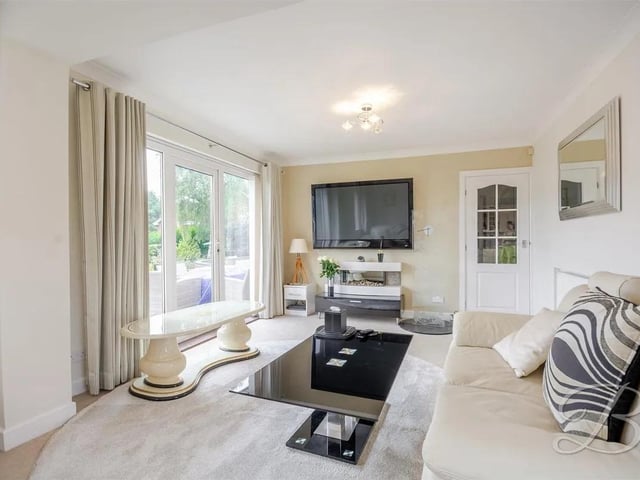 The living room is a spacious and inviting setting, beautifully enhanced with cosy carpeted flooring and a striking feature fireplace that serves as the perfect focal point.