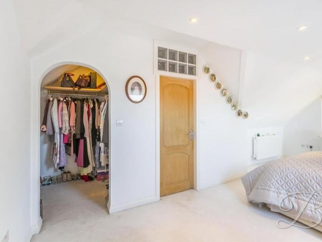 Bedroom number five boasts not only an en suite but also this walk-in wardrobe, with a carpeted floor and fitted shelves and rail.