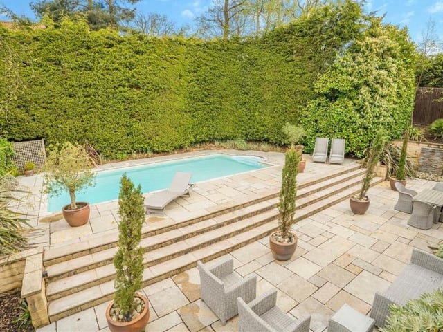 The backdrop to the swimming pool, shown here from an elevated angle, is a conifer boundary that offers excellent privacy. The steps leading up to the pool are an added attraction of a low-maintenance but well-designed rear garden.