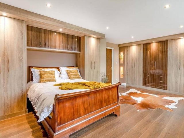 Time to move upstairs now to take in this substantial master bedroom. It boasts an extensive range of high-gloss, modern fitted furniture, including wardrobes with hanging rails and shelves, overhead storage cupboards and drawers.