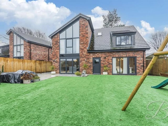At the rear, the garden has been carefully designed for style and ease, featuring a flawless artificial lawn, perimeter fencing with integrated lighting, and a paved terrace ideal for outdoor dining and relaxing.