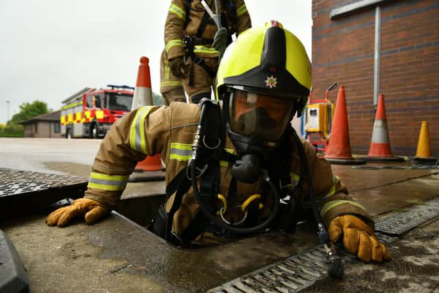 A firefighter wearing breathing apparatus enters a drain as part of a confined space training exercise.