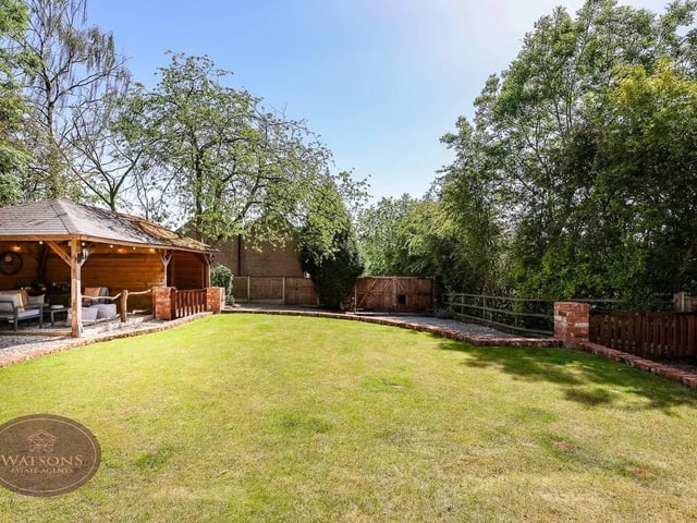 To the front of the property is a large gravelled driveway with brick boarders leading to a timber storage/seating area, raised brick based turfed lawn and patio seating area, entrance door and timber gate to the side garden.