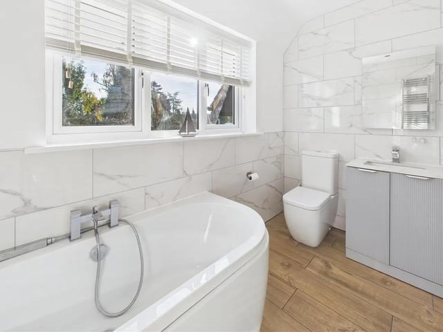 Stunning four-piece family bathroom double-ended bath, separate shower enclosure with dual-head rainfall shower, vanity unit with marble-effect sink and bathroom storage, tiled flooring and two towel radiators.