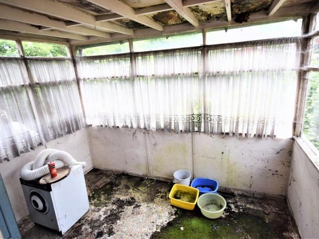 The conservatory or lean-to is a wooden construction with glazed windows and a door to the back of the bungalow. It also gives access to the garage.