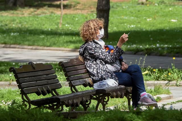 A woman with a protective mask smokes a cigarette in a park (Photo by Robert ATANASOVSKI / AFP) (Photo by ROBERT ATANASOVSKI/AFP via Getty Images)