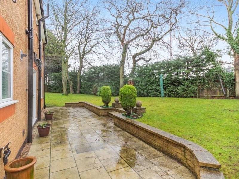 One of the nicest features of the back garden is this substantial paved patio, enclosed by a low, retaining stone wall. In the centre, two wide steps lead down to the large lawn.
