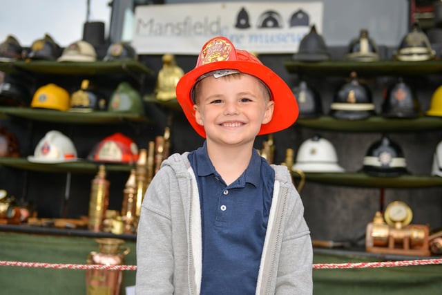 Five-year-old Alfie Driver in front of a display of helmets from Mansfield Fire Museum.