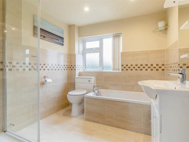 The bathroom features a contemporary four piece suite with chrome fittings comprising a tiled inset bath with mixer tap and shower handset. Corner tiled shower enclosure. Vanity unit with inset wash hand basin with mixer tap and storage cupboard beneath. There is a fitted mirror above the sink with side display shelving and inset spotlights. Low flush WC with enclosed cistern. Attractive tiling to the walls, tiled floor, electric underfloor heating, ceiling spotlights, extractor fan and obscure double glazed window to the rear elevation.