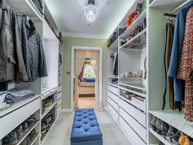 Stunning walk in wardrobe in the master suite with carpeted floor, fitted shelving and drawers, central heating radiator sensor, coving, activated lighting and opaque window to the side elevation.