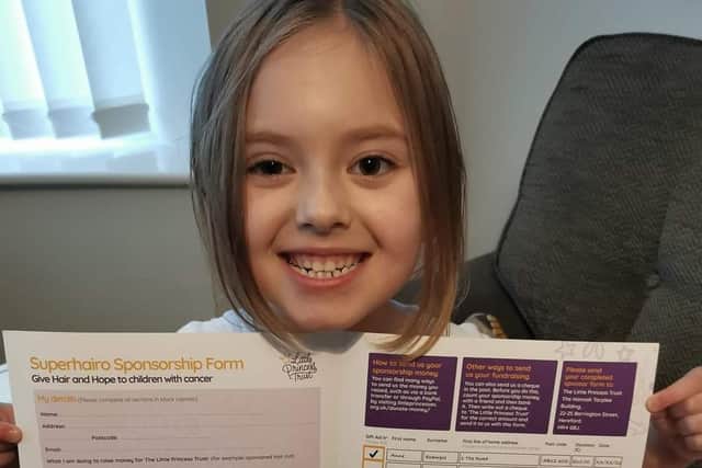Little Willow who is cutting her hair to help other children, seen with her Little Princess Trust application form